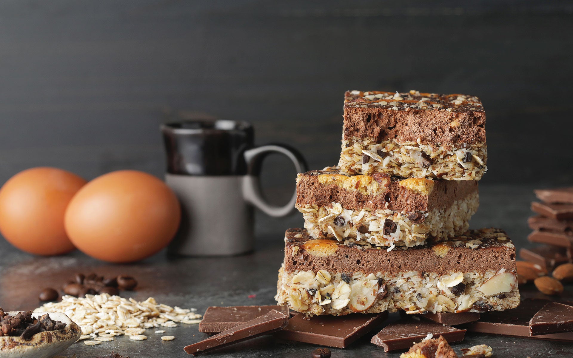 Condition One Dark Chocolate Espresso High Protein Bars surrounded by wholefood ingredients such as eggs, coffee beans, oats, and almonds.
