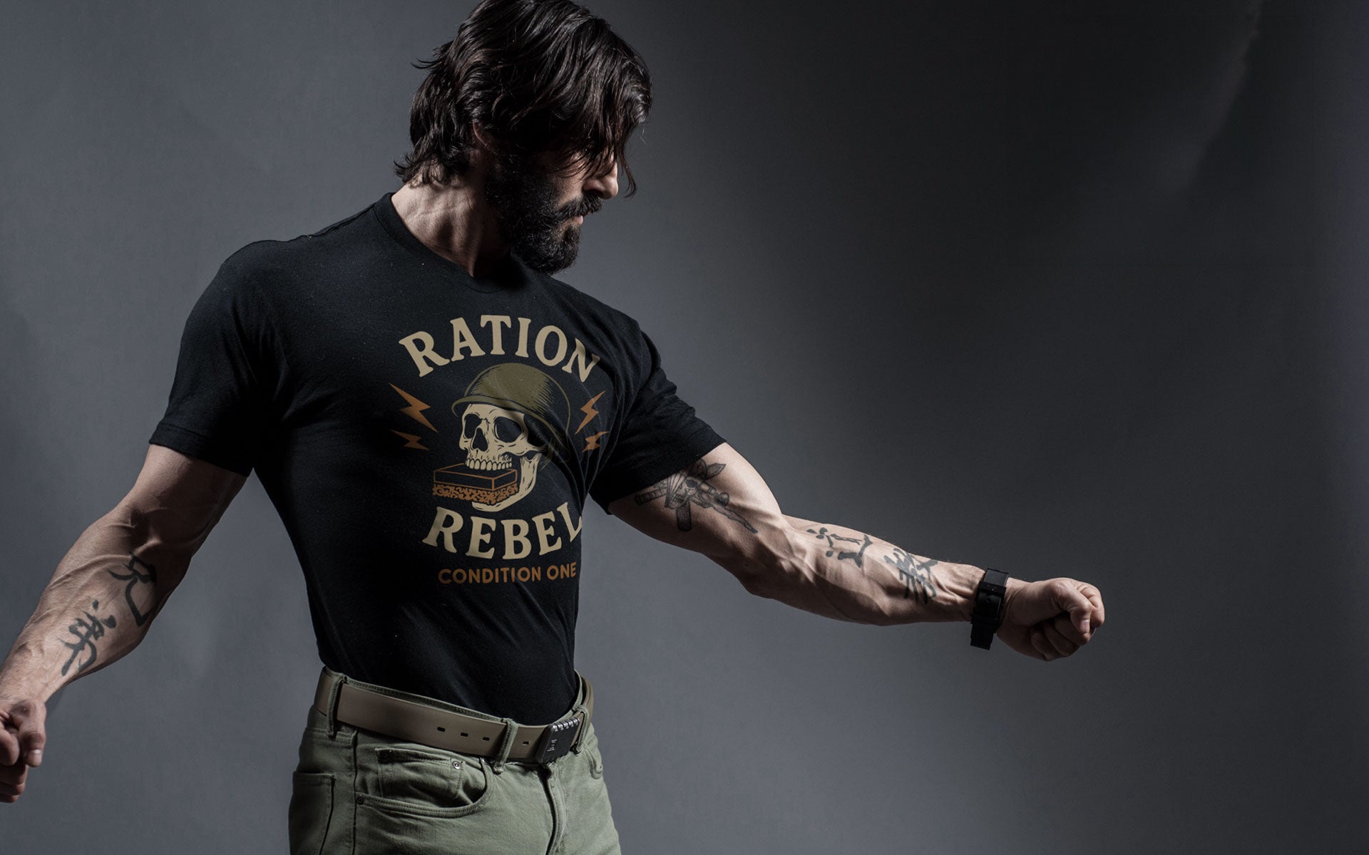 Rudy Reyes wearing a black t-shirt with 'Ration Rebel' design against a dark background