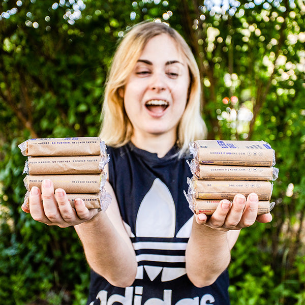 Woman holding stacks of Condition One protein bars.