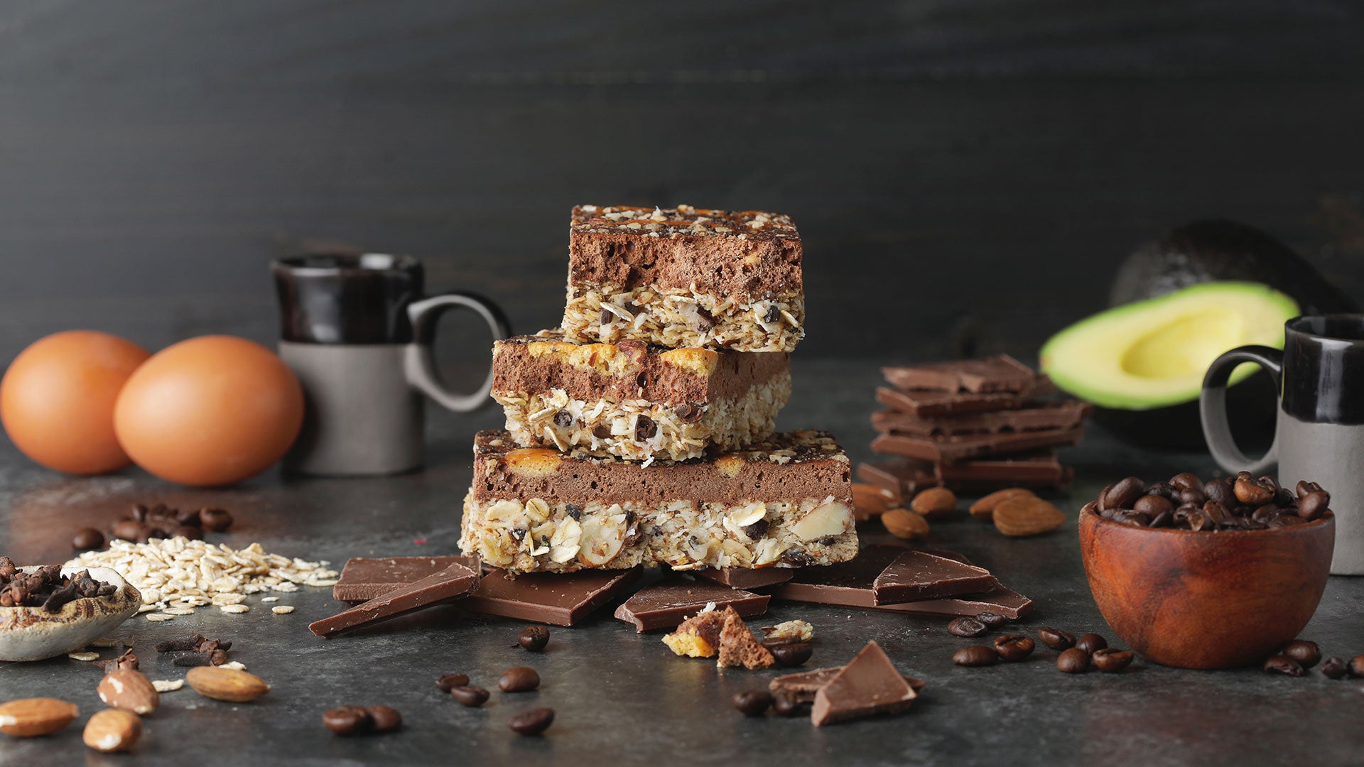 Condition One Dark Chocolate Espresso High Protein Bars surrounded by wholefood ingredients such as eggs, coffee beans, oats, and almonds.