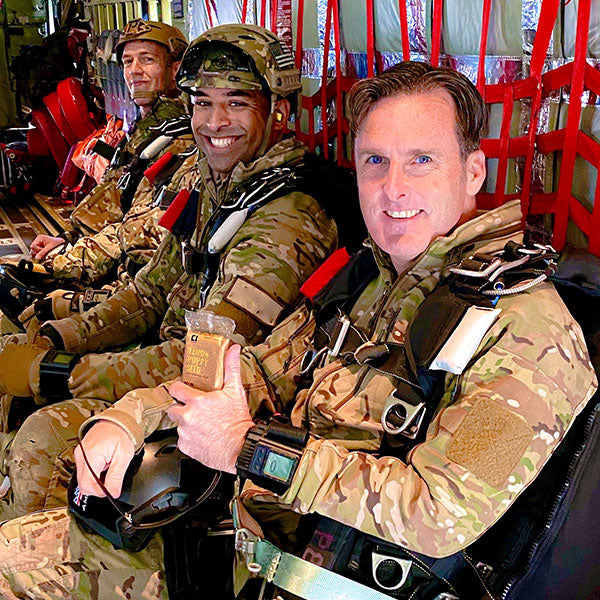 Three soldiers on an airplane with one holding a Condition One protein bar.