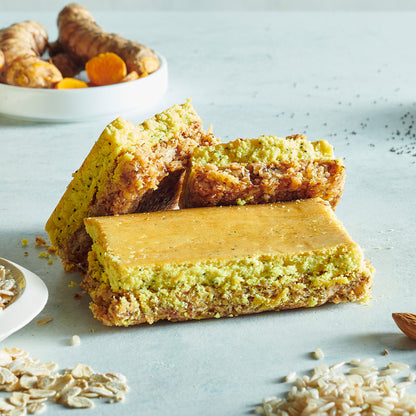 A high-protein nutrition bar with layers visible, showing the lemon poppy seed flavor showing real ingredients such as oats and almonds.