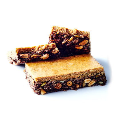 A photo of two high-protein bars with visible nuts and seeds, one bar is cut to show the inside, with a focus on the texture and composition of the bars.
